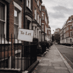 Row of London townhouses with 'To Let' sign on black fence.