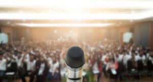 Microphone on stage at Landlord Today event with audience in background.
