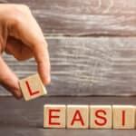 Hand placing letter block to spell 'EASING' on wooden surface.