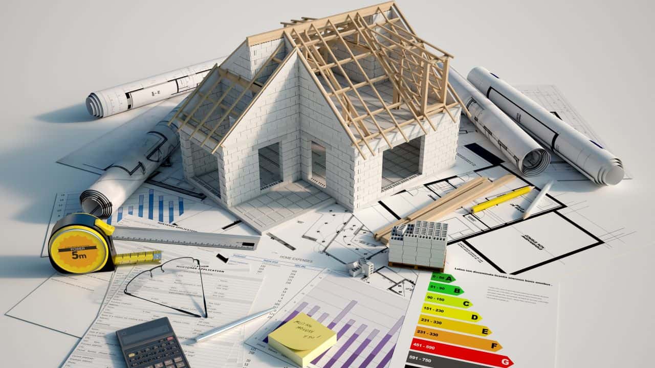 Architectural house model with blueprints and tools for construction planning.