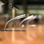Close-up of conference room microphones on a wooden table.