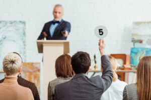 Man raising hand with number 5 at property event, landlord seminar or auction.