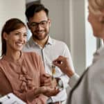 Happy tenants receiving keys from landlord in modern apartment.