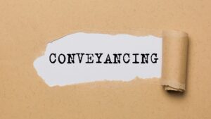 Conveyancing document with torn paper revealing the word 'CONVEYANCING'.