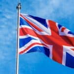 Union Jack flag waving against a blue sky, symbolising UK pride and identity.