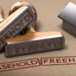 Leasehold and freehold stamps with a small house model on a beige background.