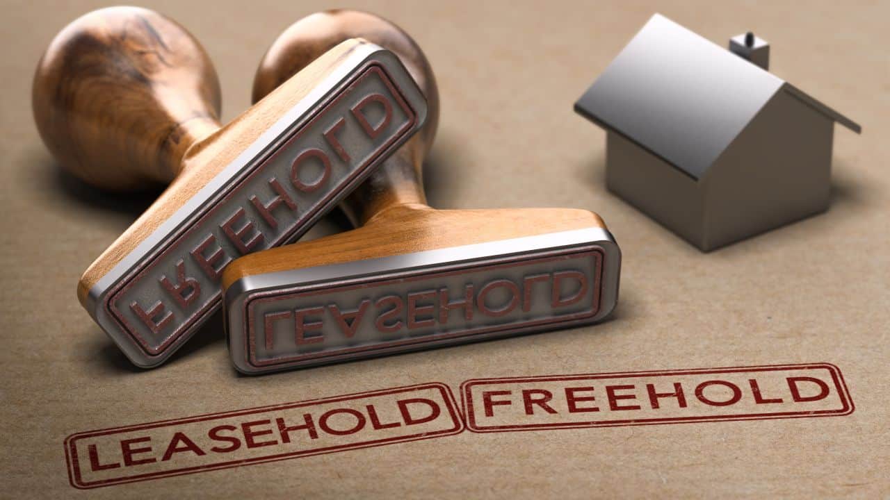 Leasehold and freehold stamps with a small house model on a beige background.