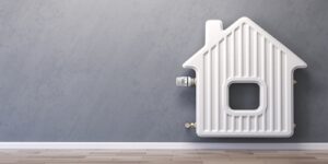 Unique house-shaped radiator mounted on a grey wall for home heating.