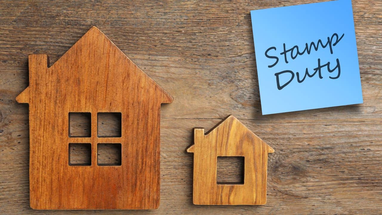 Wooden house models with stamp duty note on wooden surface.