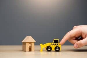 Miniature house and toy bulldozer representing property development.
