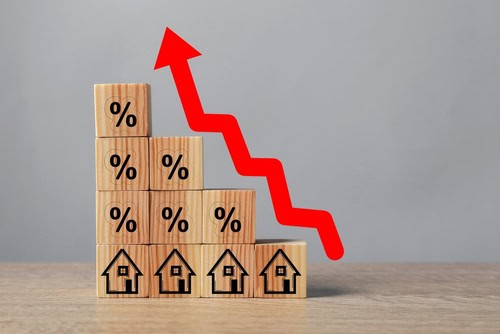 Wooden blocks with percentage signs and houses showing rising interest rates.