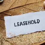 Leasehold written on torn paper with sandy background and seashells.