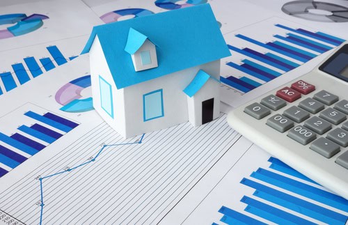 Miniature house model with financial charts and calculator for landlords.