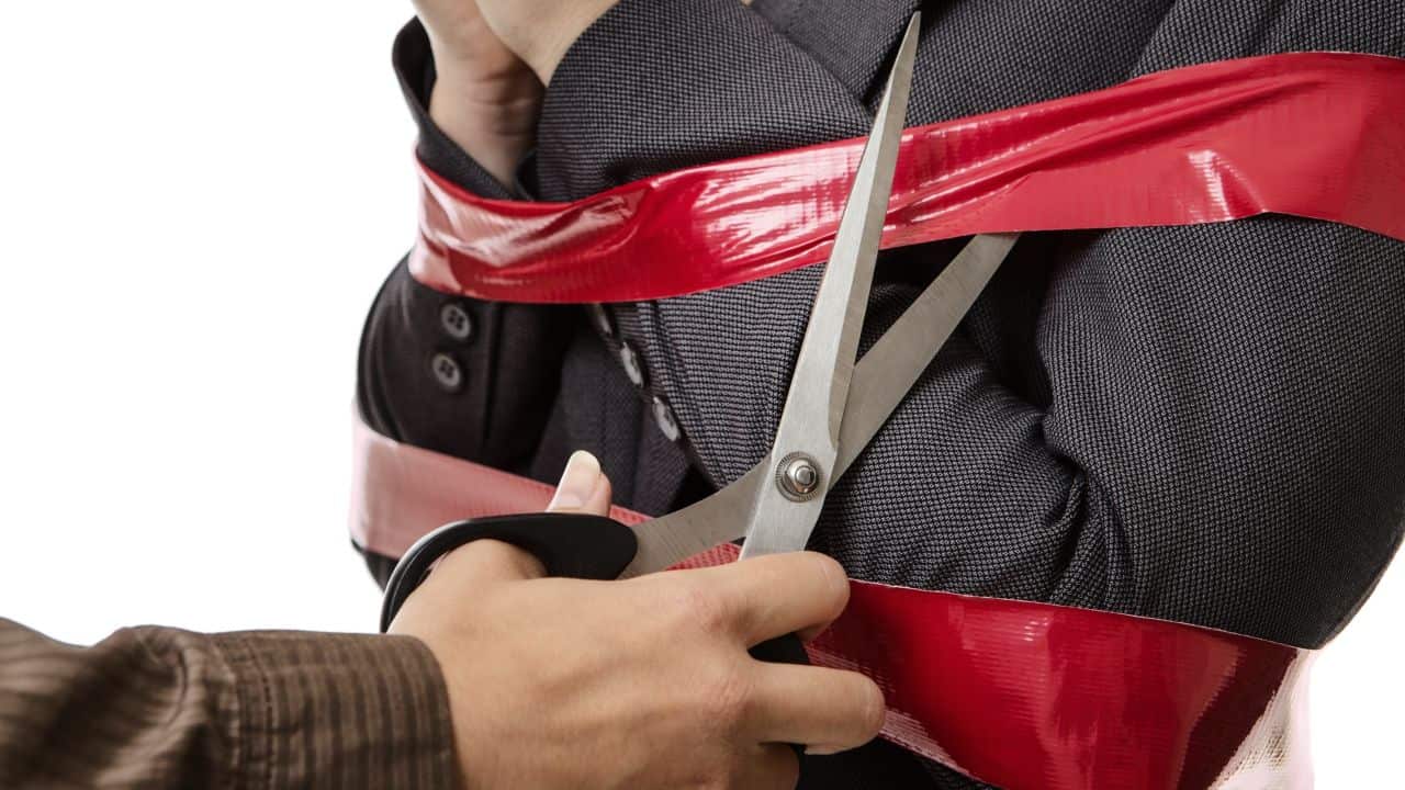 Person cutting red tape with scissors, symbolising property restrictions.