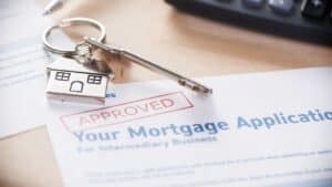 Key and house-shaped keychain on approved mortgage application document.