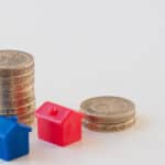 Miniature house models with stacked coins symbolising property investment and finance.