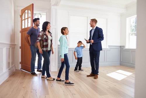 Family viewing a property with a landlord in a bright, spacious room.