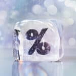 Ice cube with percentage symbol representing interest rates or discounts for landlords.