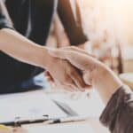 Two people shaking hands in a professional setting for landlord-related content.