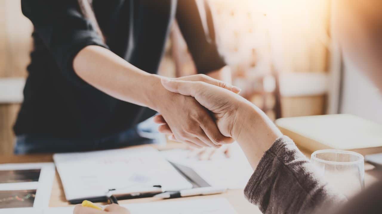 Two people shaking hands in a professional setting for landlord-related content.