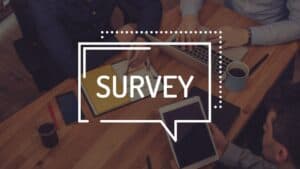 Survey concept with people discussing at a table with tablets and coffee.