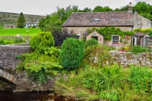 Traditional stone cottage surrounded by vibrant greenery and garden.